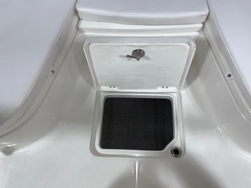 Slide: The Image of 2026 Robalo 226 Cayman boat storage compartment with black mat and secure latch. - 22