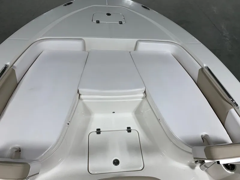 Slide: The Image of 2026 Robalo 226 Cayman boat interior with white cushioned seating and storage compartments. - 27