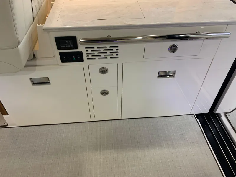 Slide: The Image of 2023 Regal 36XO yacht interior cabinetry with control panel and storage drawers. - 10