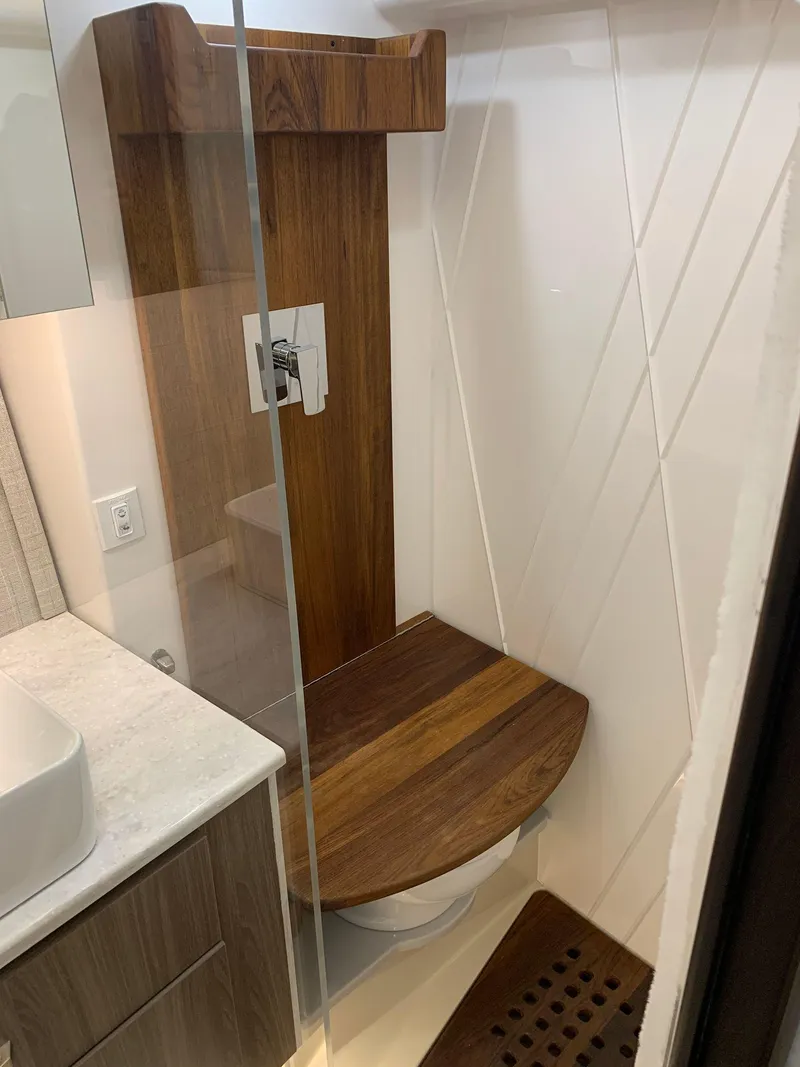 Slide: The Image of 2023 Regal 36XO yacht bathroom with modern wooden shower seat and glass enclosure. - 26
