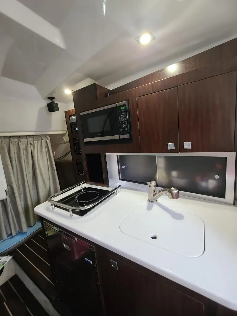 Slide: The Image of 2018 Monterey 295 Sport Yacht interior kitchen with sink, stove, and microwave. - 13