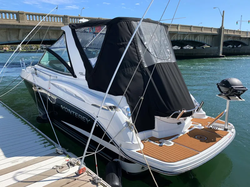 Slide: The Image of 2018 Monterey 295 Sport Yacht docked near a bridge, featuring sleek design and black canopy. - 2