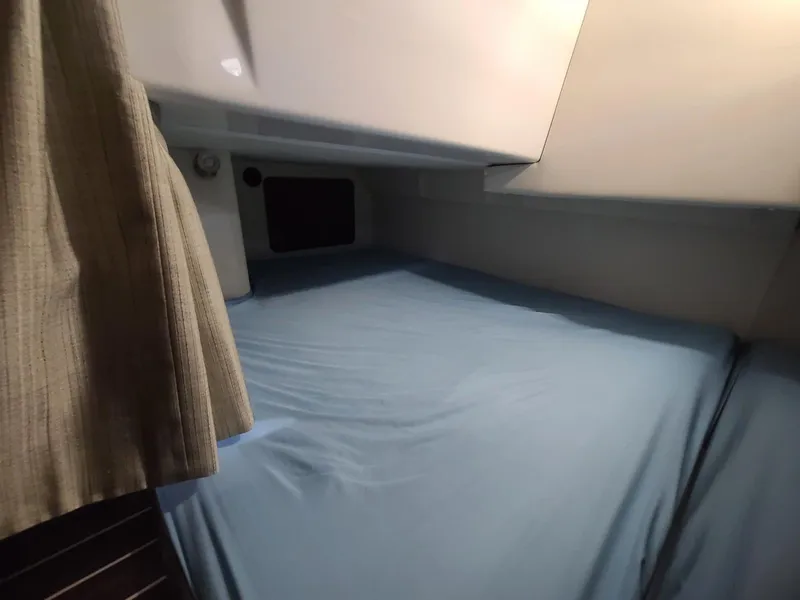 Slide: The Image of 2018 Monterey 295 Sport Yacht cabin with blue bedding and curtain. - 9