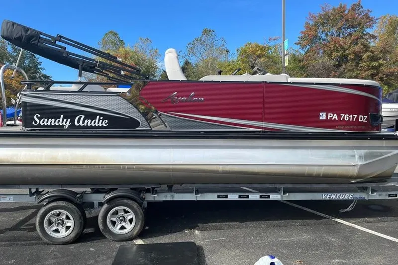 The Image of 2021 Avalon 2285 LSZ Cruise Rear Bench pontoon boat on trailer, labeled "Sandy Andie." - 0