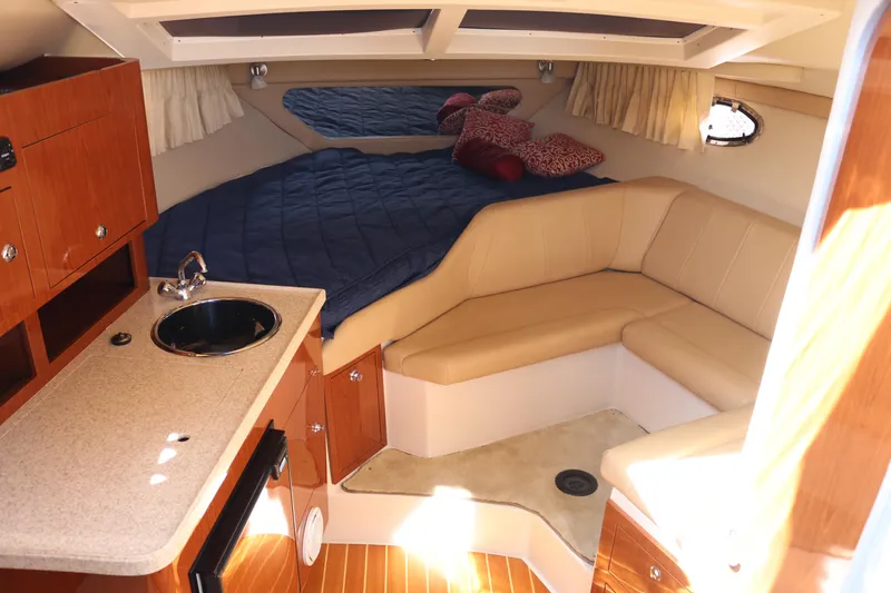 Slide: The Image of 2009 Regal 3060 Express Cruiser cabin with kitchenette, seating, and bed. - 10