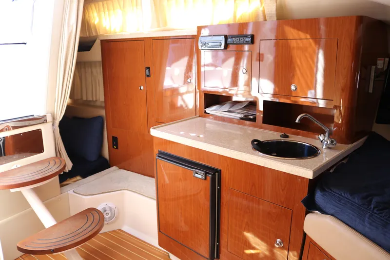 Slide: The Image of 2009 Regal 3060 Express Cruiser interior with kitchenette, wood cabinetry, and seating area. - 11