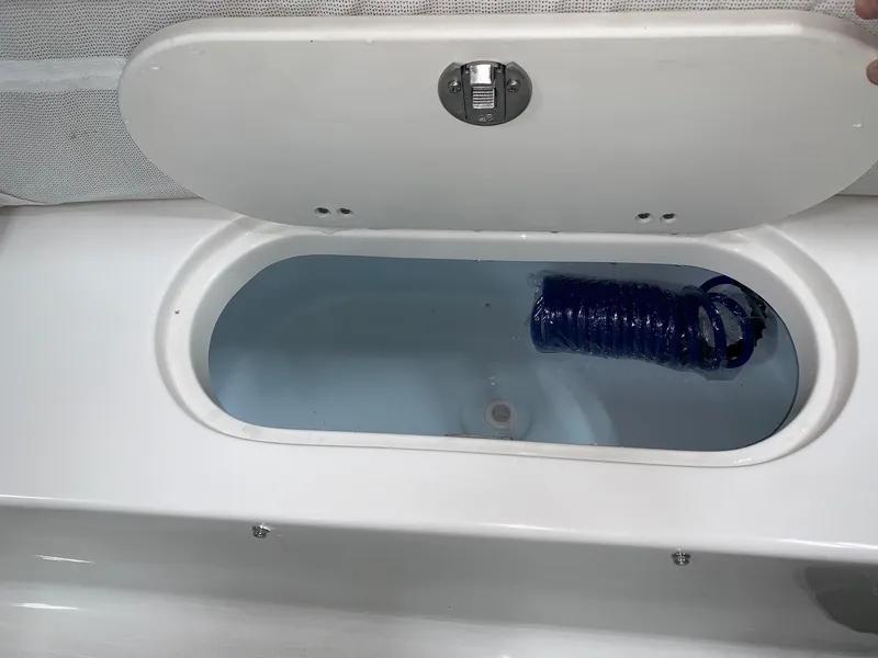 Slide: The Image of Open storage compartment on 2024 Key West 189 FS boat with coiled blue hose. - 5