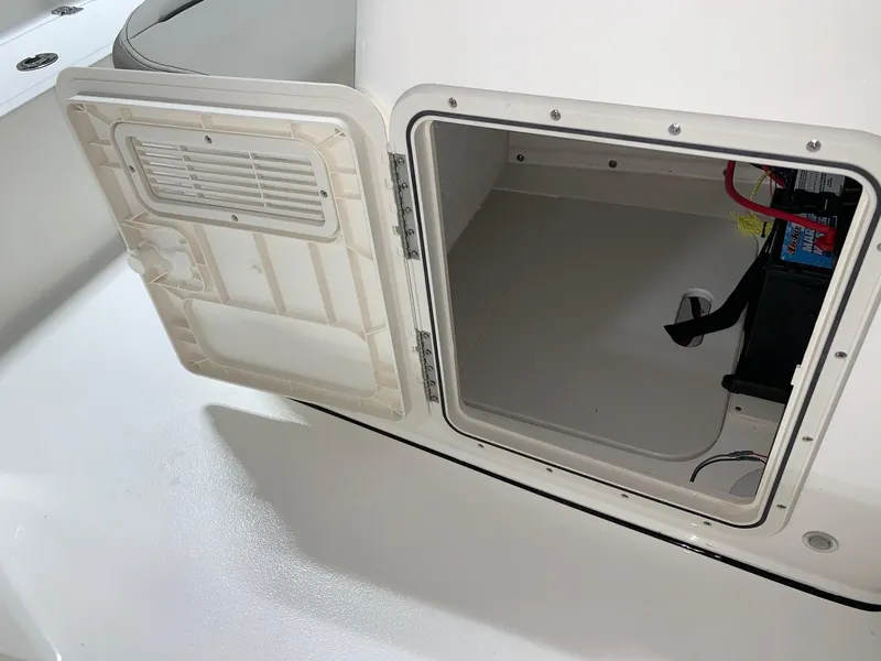 Slide: The Image of 2026 Key West 188 Bay Reef boat storage compartment with open hatch and visible battery. - 19