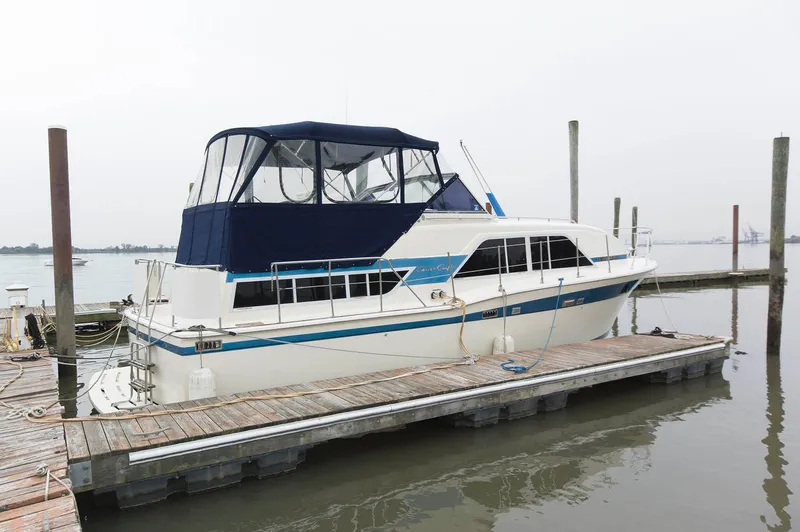 The Image of 1984 Chris-Craft 350 Catalina docked, featuring blue canopy and classic design. - 0