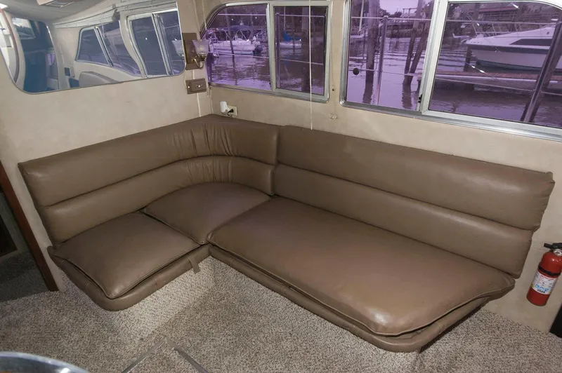 Slide: The Image of 1984 Chris-Craft 350 Catalina interior with brown leather seating and marina view through windows. - 11