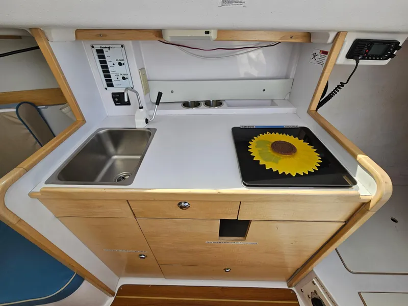 Slide: The Image of 2015 Catalina 275 Sport interior kitchen with sink, stove, and sunflower design. - 3