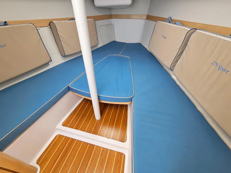Slide: The Image of 2015 Catalina 275 Sport interior cabin with blue cushions and wooden flooring. - 4