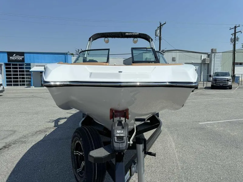 Slide: The Image of 2021 MasterCraft NXT24 boat on a trailer in a parking lot. - 2