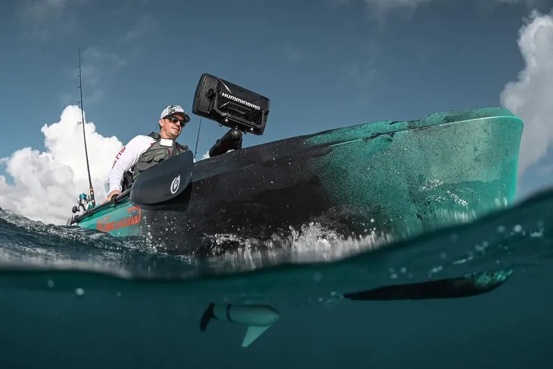 Slide: The Image of 2023 Old Town 106 Sportsman Minn Kota Power kayak on water, with person fishing. - 1