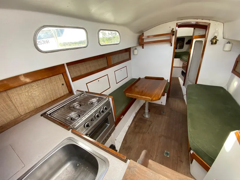 Slide: The Image of Interior of a 1968 Pearson Wanderer sailboat with kitchen, dining area, and green seating. - 10