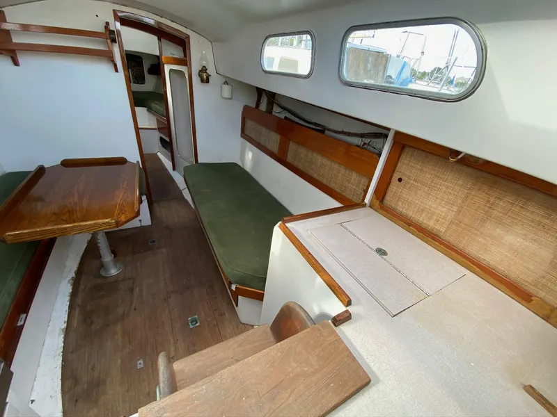 Slide: The Image of 1968 Pearson Wanderer sailboat interior with wooden furnishings and green cushions. - 12