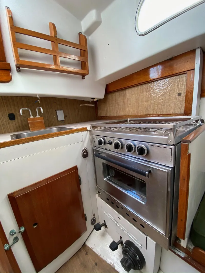 Slide: The Image of 1968 Pearson Wanderer yacht kitchen with stove, sink, and wooden cabinetry. - 17