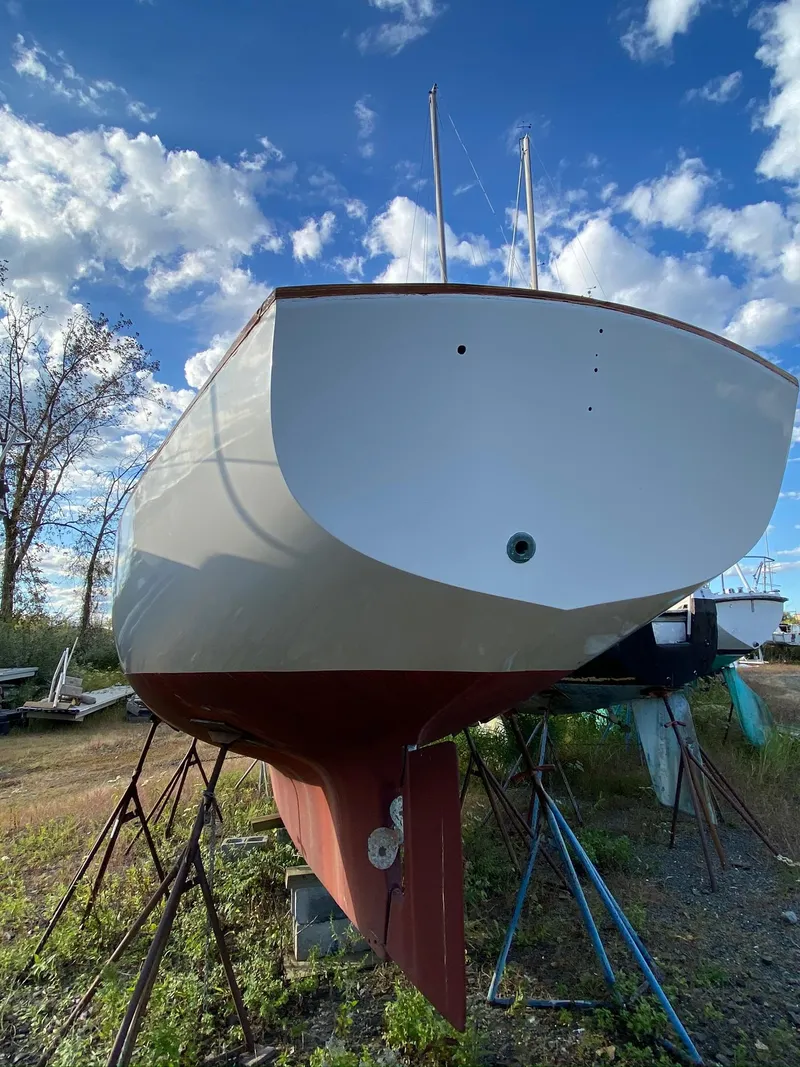 Slide: The Image of 1968 Pearson Wanderer sailboat on stands, under a blue sky with clouds. - 2