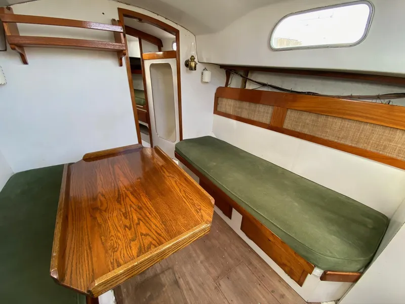 Slide: The Image of 1968 Pearson Wanderer sailboat interior with wooden table, green cushions, and cozy seating area. - 20