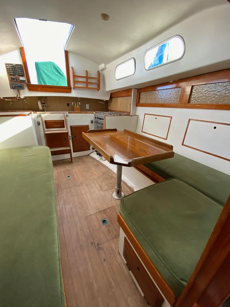 Slide: The Image of 1968 Pearson Wanderer sailboat interior with wooden table, green cushions, and natural light. - 21