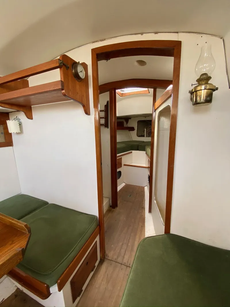 Slide: The Image of 1968 Pearson Wanderer sailboat interior with green cushions and wooden accents. - 22