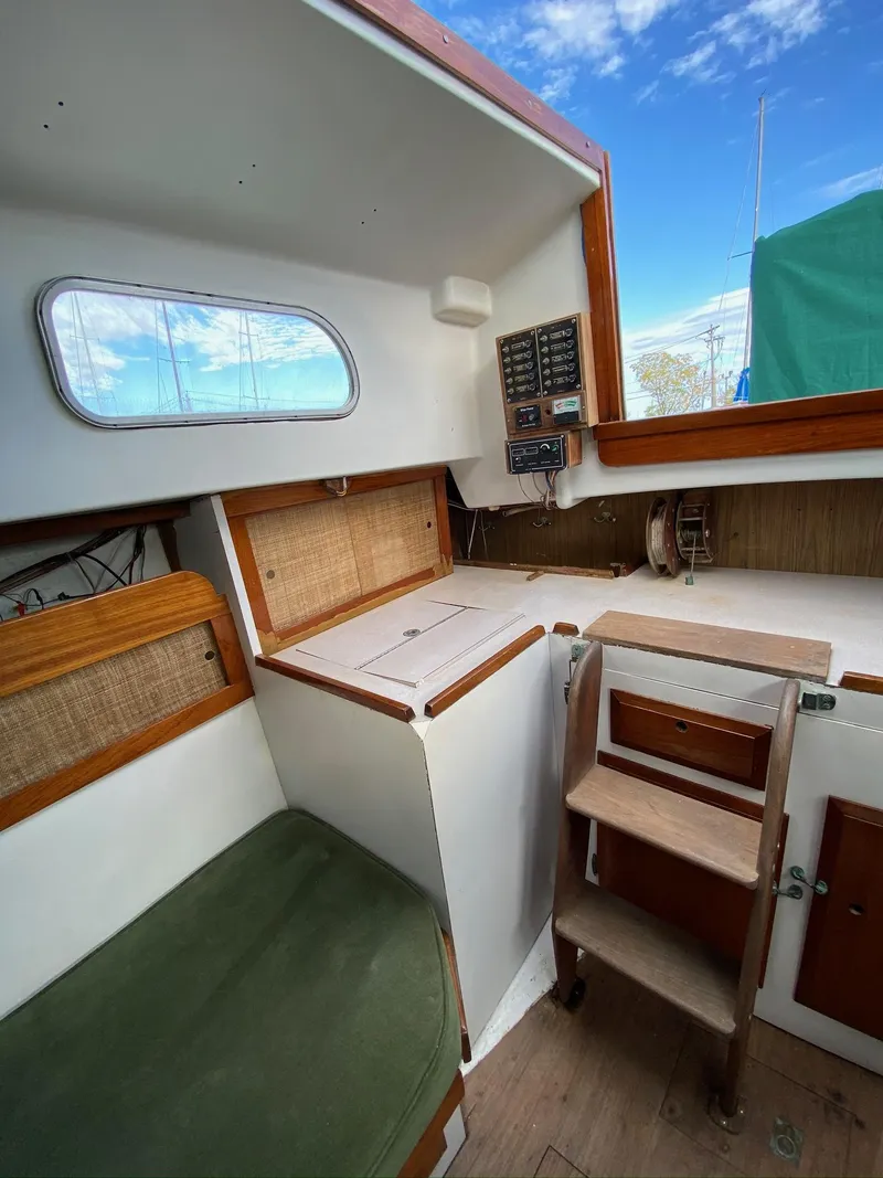 Slide: The Image of 1968 Pearson Wanderer sailboat interior with wooden steps and green cushion under a blue sky. - 27