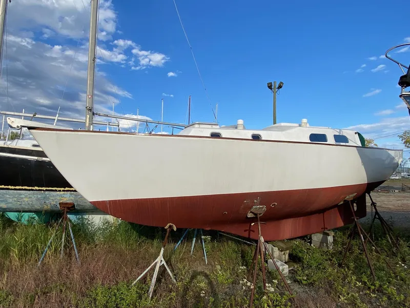 Slide: The Image of 1968 Pearson Wanderer sailboat on stands, under a clear blue sky. - 4