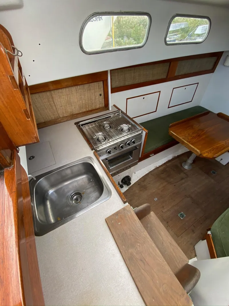 Slide: The Image of 1968 Pearson Wanderer boat interior with kitchen, stove, sink, and dining area. - 9