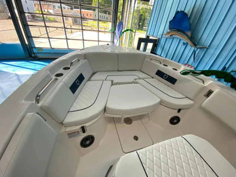 Slide: The Image of 2025 Sea Fox 268 Commander boat interior with white cushioned seating in a showroom. - 20