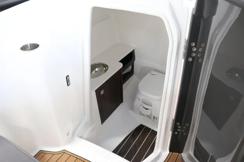Slide: The Image of 2018 Monterey M-65 boat interior with compact bathroom, featuring a toilet and sink. - 10