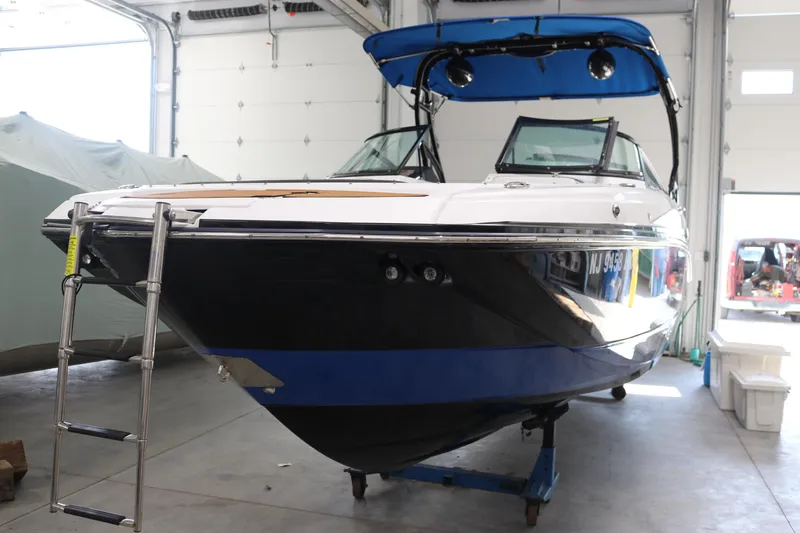 Slide: The Image of 2018 Monterey M-65 boat in garage, black and blue hull, ladder attached. - 2