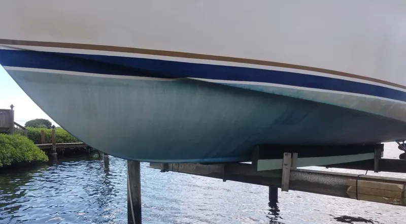 Slide: The Image of 1977 Pace Wahoo boat hull on lift, showing blue and white paint near water. - 18