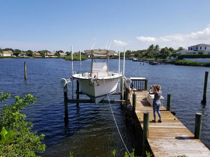 Slide: The Image of A 1977 Pace Wahoo boat docked on a sunny day, with a person taking photos. - 2
