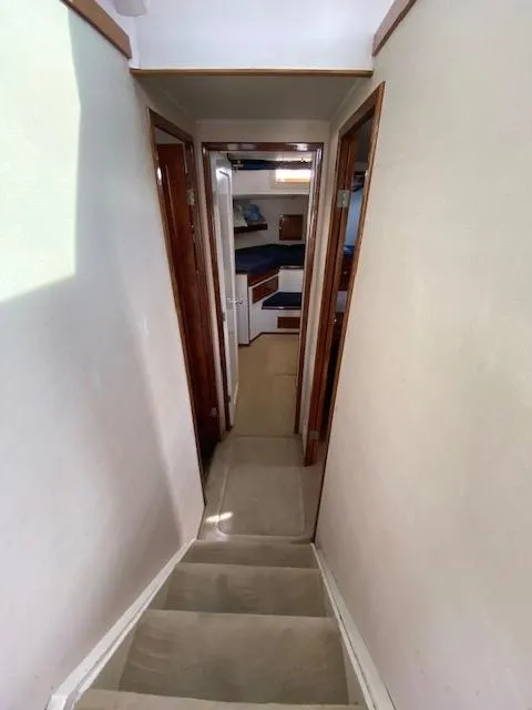 Slide: The Image of Interior hallway of a 1973 Uniflite 42 Flybridge boat, featuring wooden doors and carpeted stairs. - 21