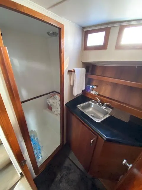Slide: The Image of 1973 Uniflite 42 Flybridge bathroom with sink, shower, and wooden cabinetry. - 18