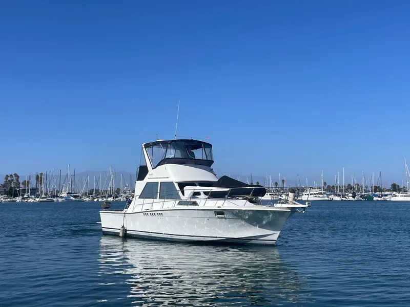 Slide: The Image of 1973 Uniflite 42 Flybridge boat on calm water with marina background. - 2