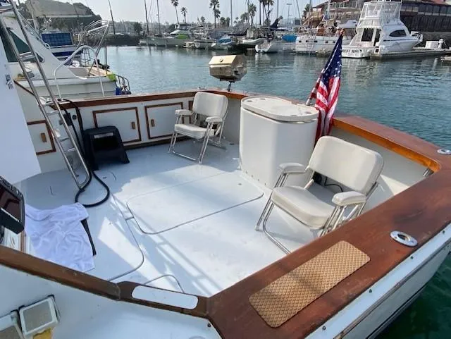 Slide: The Image of 1973 Uniflite 42 Flybridge boat deck with chairs, American flag, and marina view. - 29