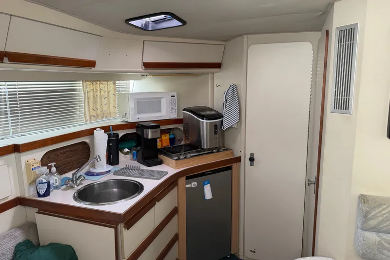Slide: The Image of Compact kitchen area in a 1988 Carver 32 Montego boat with sink, microwave, and appliances. - 13