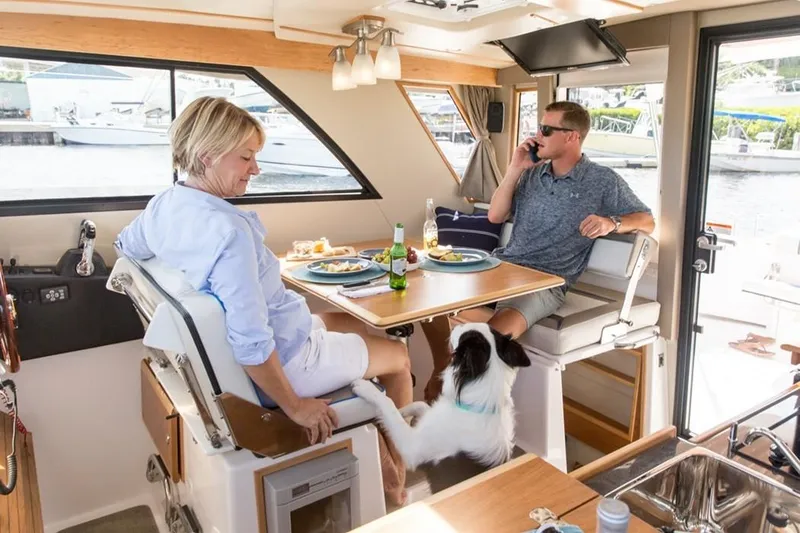 Slide: The Image of Couple dining with dog on 2020 Cutwater C 32 CB boat interior. - 15