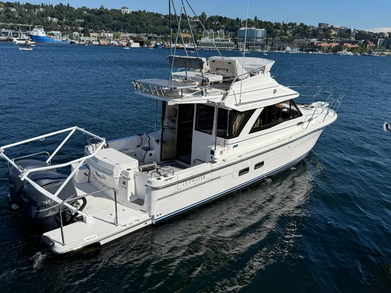 Slide: The Image of 2020 Cutwater C 32 CB boat cruising on a scenic lake with a city backdrop. - 18