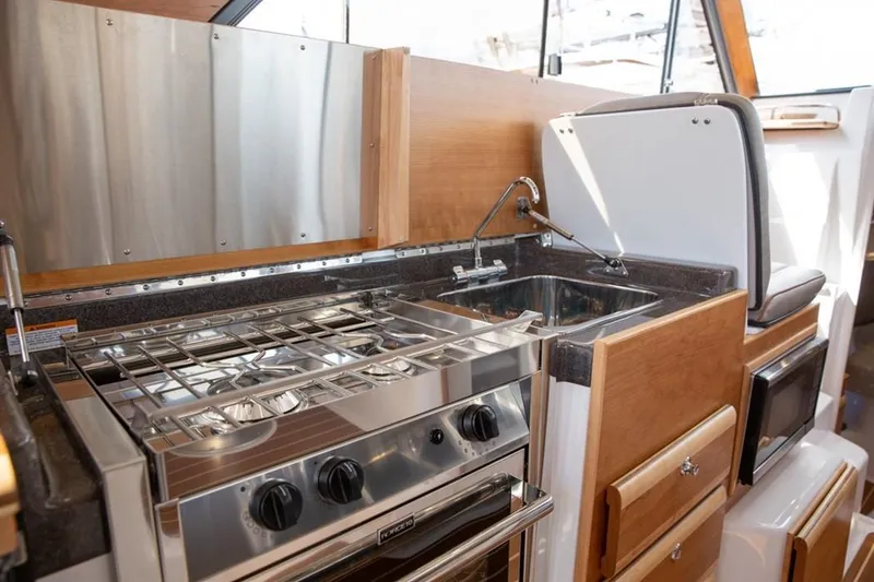 Slide: The Image of Compact kitchen in 2020 Cutwater C 32 CB boat with stove, sink, and wooden cabinetry. - 8
