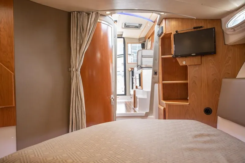 Slide: The Image of Interior of 2020 Cutwater C 32 CB boat, featuring wood paneling, bed, and mounted TV. - 9