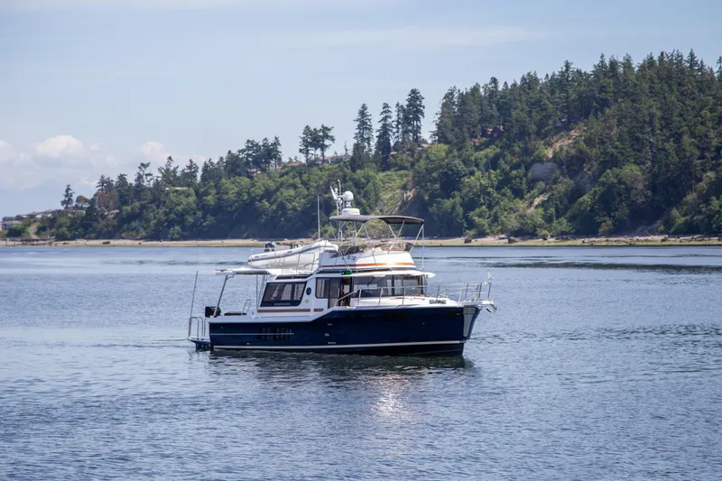 Slide: The Image of 2025 Ranger Tugs R-43 Command Bridge Luxury Edition cruising on a scenic lake. - 3