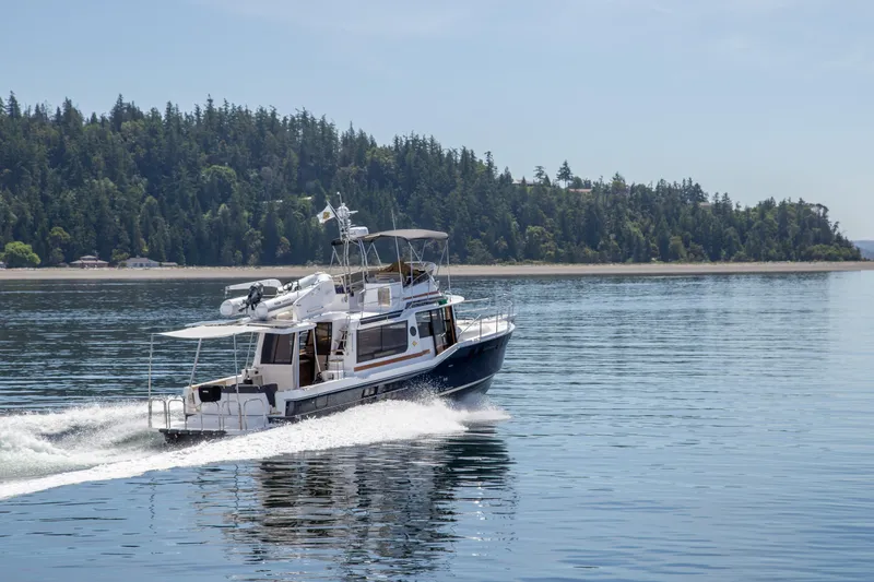 Slide: The Image of 2025 Ranger Tugs R-43 Command Bridge Luxury Edition cruising on a serene lake. - 4