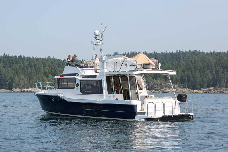 Slide: The Image of 2025 Ranger Tugs R-43 Command Bridge Luxury Edition on serene water, forested background. - 6