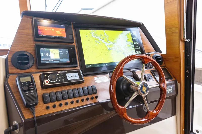 Slide: The Image of 2025 Ranger Tugs R-43 Sedan helm with navigation screens and wooden steering wheel. - 7
