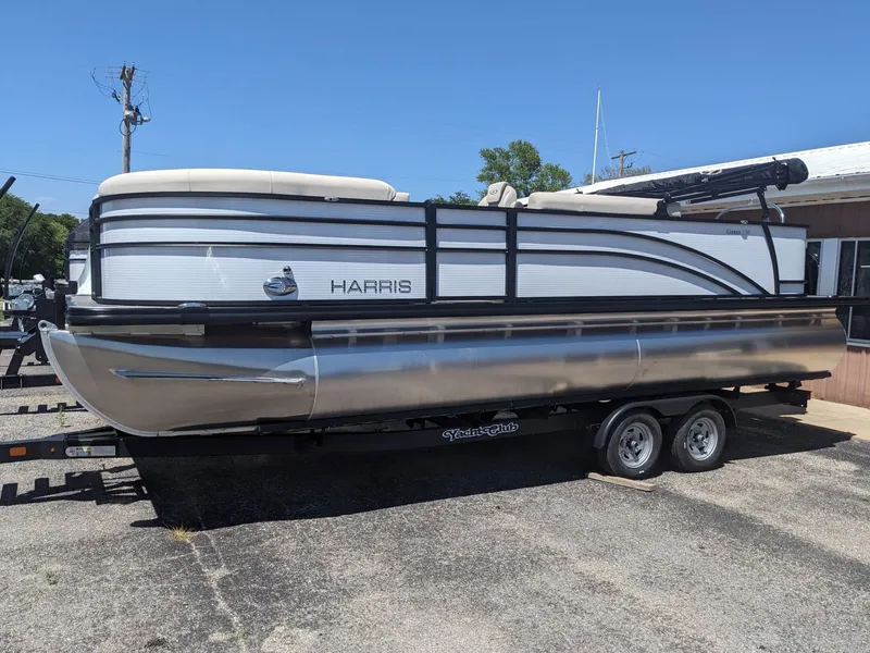 Slide: The Image of 2023 Harris Cruiser 230 pontoon boat on a trailer, parked outdoors. - 1
