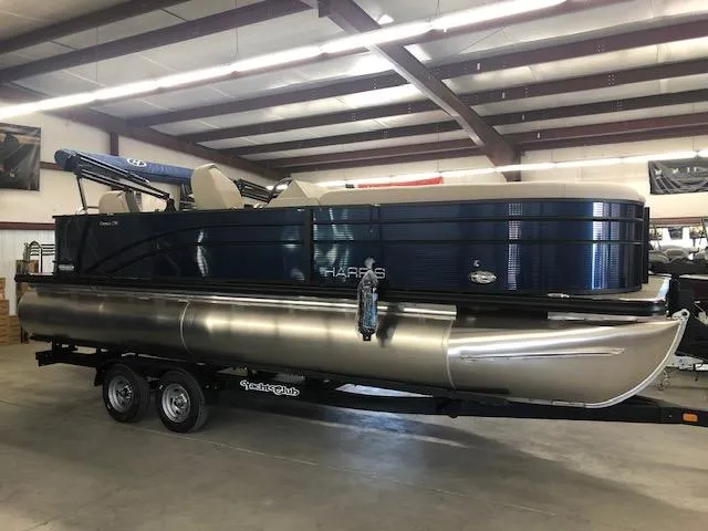 Slide: The Image of 2023 Harris Cruiser 230 pontoon boat in showroom, side view. - 2
