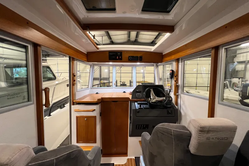 Slide: The Image of Interior of a 2021 Sargo 25 boat with helm, seating, and wooden accents. - 17