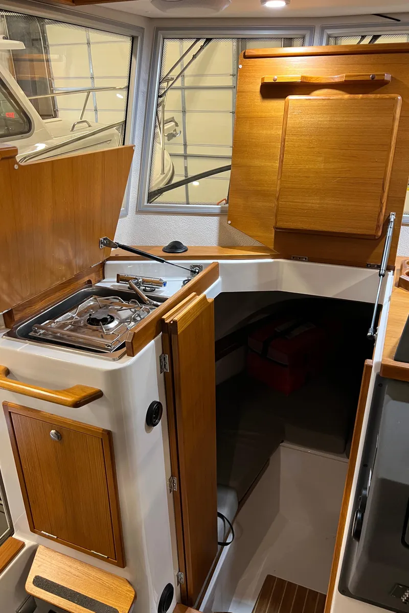 Slide: The Image of Interior of 2021 Sargo 25 boat with wooden cabinetry and compact kitchen area. - 19